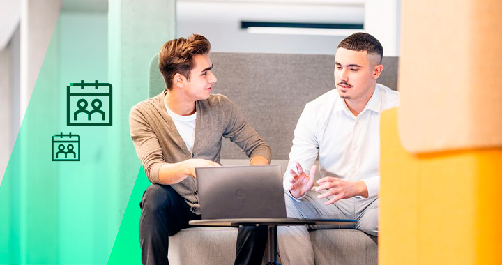 Ein erfahrener Mitarbeiter führt Gespräch mit einem jungen Mann in einem hellen Büro.