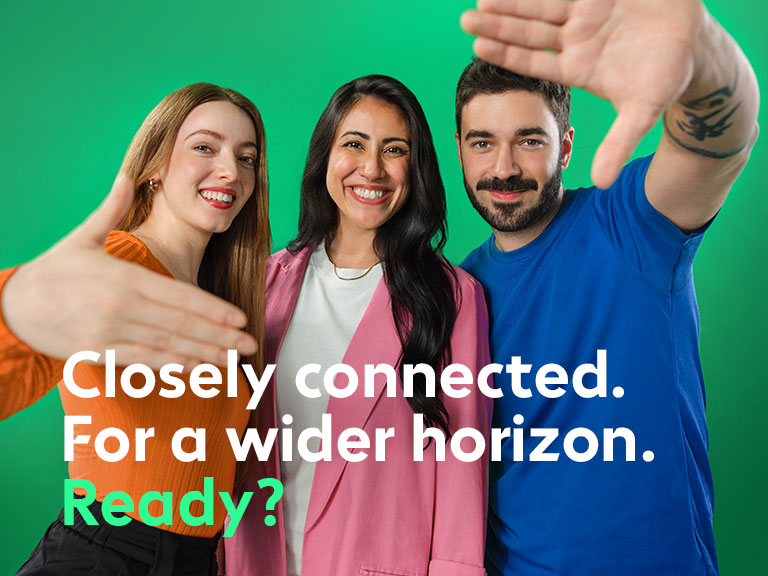 A group of three people smile at the camera and extend their hands invitingly.