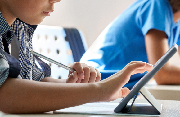 Ein Junge benutzt ein Tablet zum Lernen in der Schule.