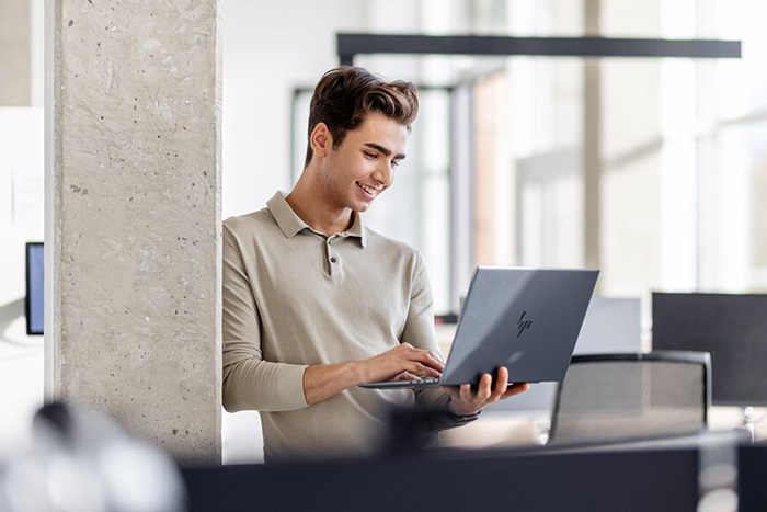 Ein Student steht und hält in den Händen sein Laptop
