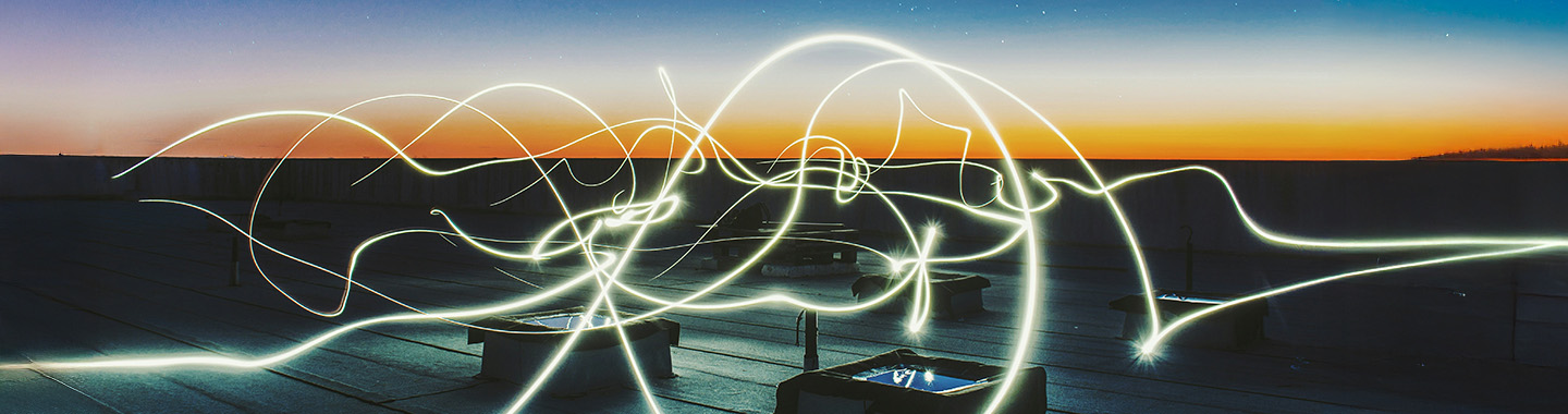 Light trails at dusk on a rooftop terrace with a clear horizon and urban background