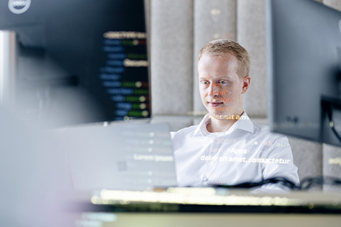 Ein junger Mann schaut auf einen Monitor und arbeitet