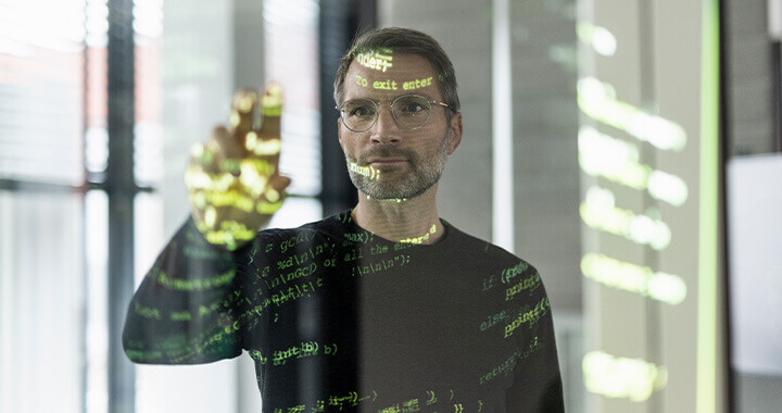 IT-Mitarbeiter bedient einen durchsichtigen Screen mit dem Code.