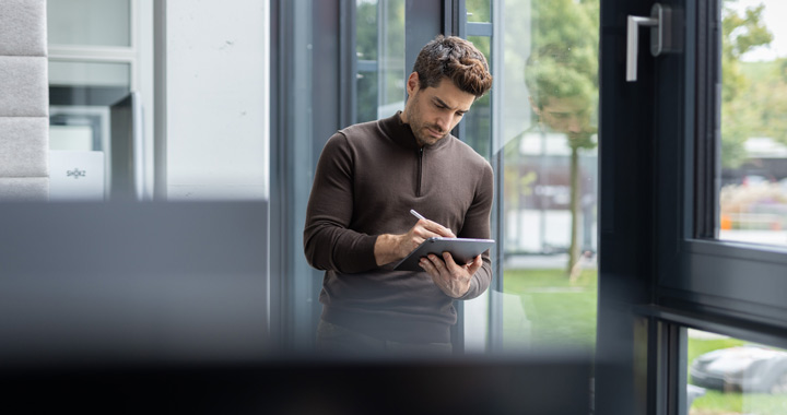 Mann schreibt auf einem Tablet