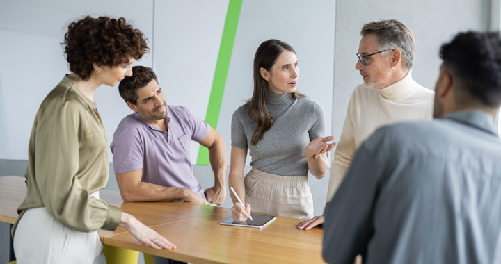 Fünf Menschen stehen im Büro und unterhalten sich