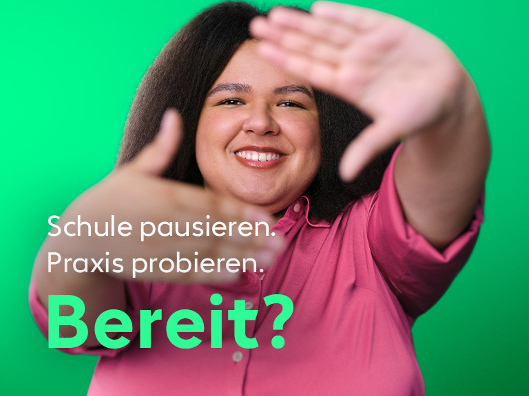 Eine junge Frau blickt lächelnd in die Kamera und streckt die Hände einladend nach vorn.